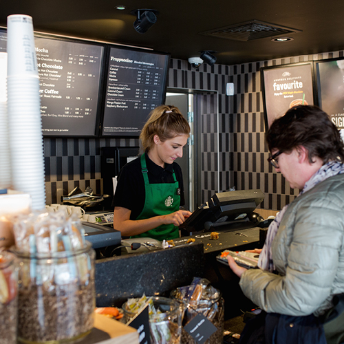 Person serving coffee in a Starbucks counter